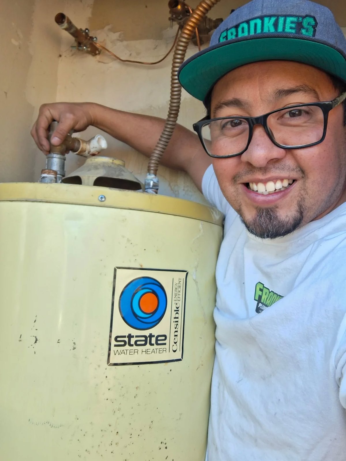 Frankie in his Frankie's cap next to an old water heater on a job