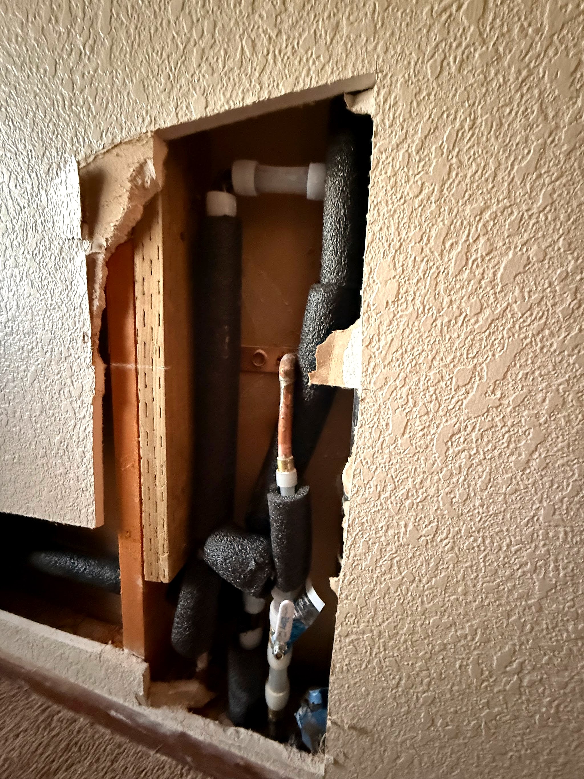 Wall opened up to reach the pipes and the bathroom manifold