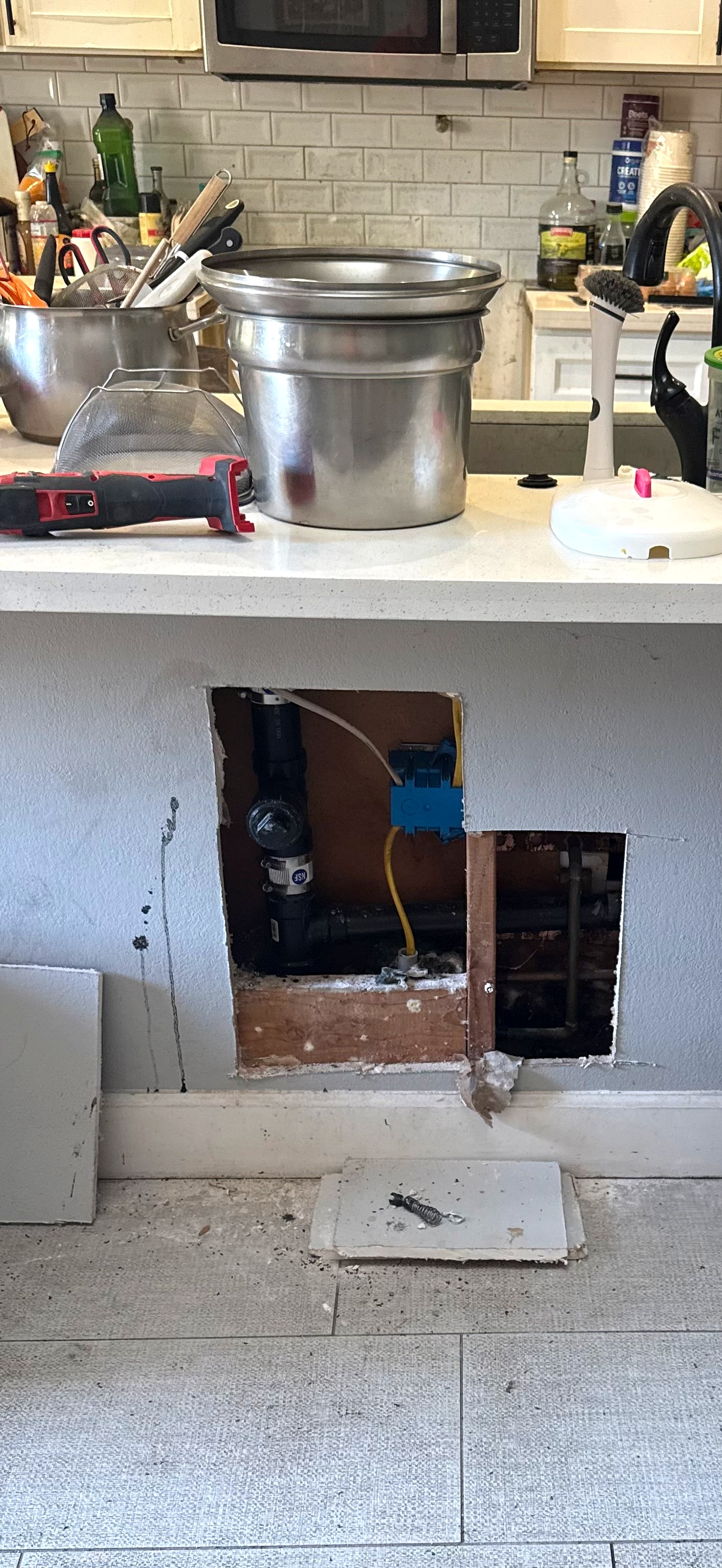 Kitchen island with access holes cut to reach the pipes
