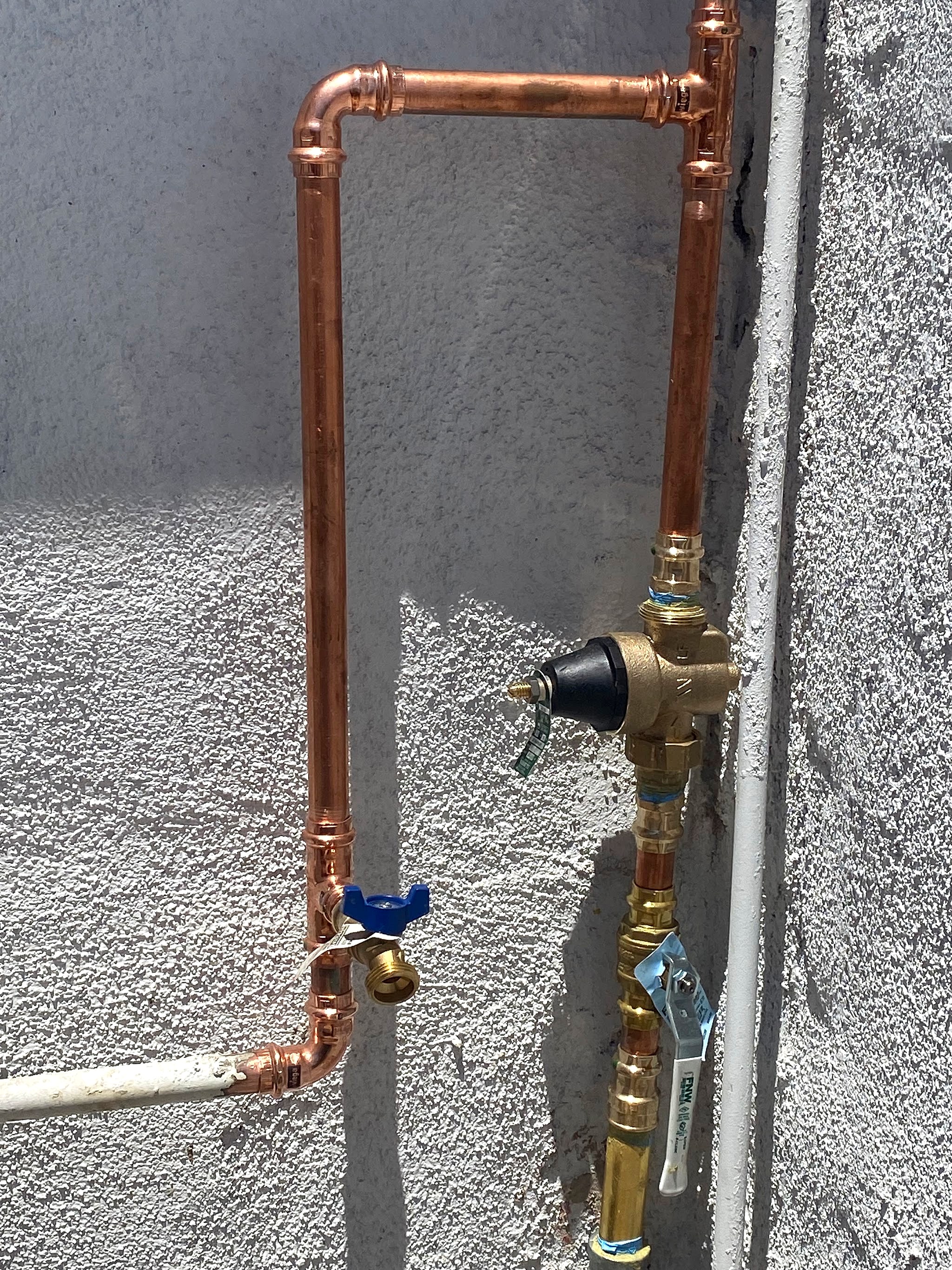 New copper line and pressure regulator on a stucco wall